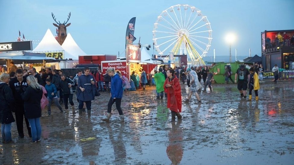 Посетители музыкального фестиваля Rock am Ring пробираются через грязь после сильного ливня (04 июня 2016 г.)