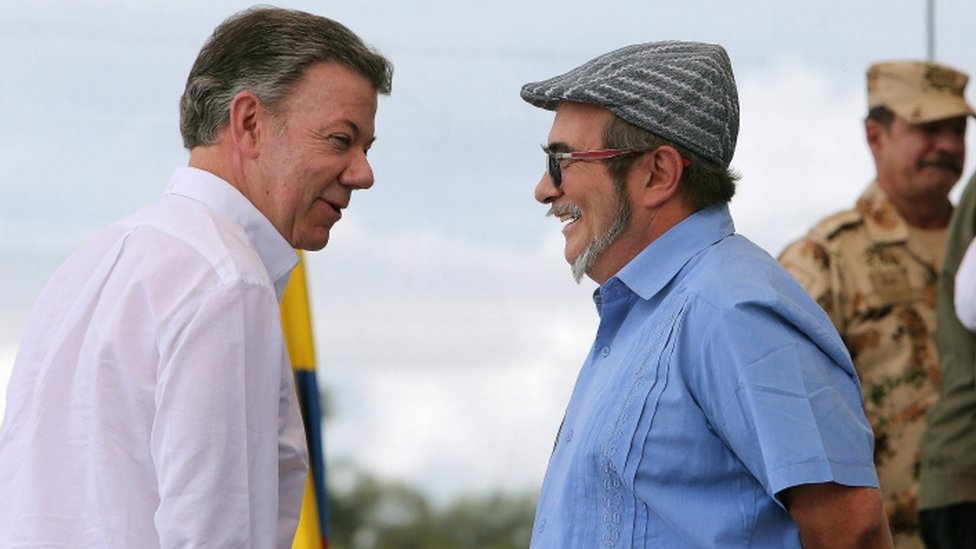 Президент Колумбии Хуан Мануэль Сантос (слева) и главный лидер Революционных вооруженных сил Колумбии (FARC) Родриго Лондоно (справа), он же Тимоченко, разговаривают друг с другом во время церемонии разоружения в одном из бывших военных опорных пунктов Фарсов, Месетас, Колумбия , 27 июня 2017 г.