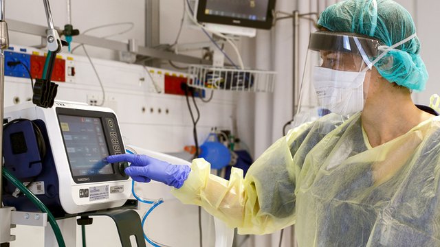 Enfermeiro checa dados no monitor de um paciente em uma UTI