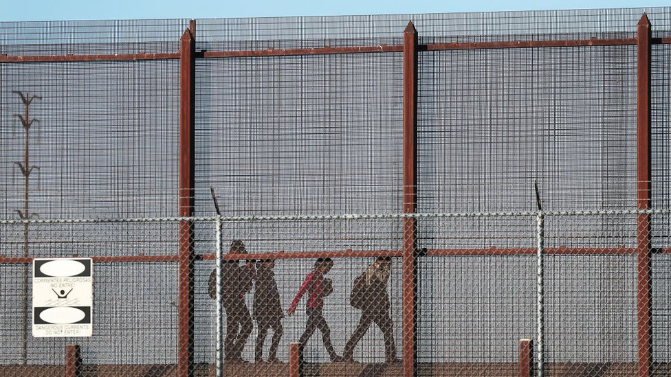 Мигранты вместе идут вдоль американо-мексиканской пограничной стены возле Эль-Пасо 4 июня 2019 г.