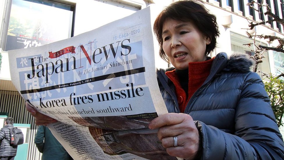 Una mujer leyendo un periódico en Tokio con noticias sobre el programa de armas de Corea del Norte.