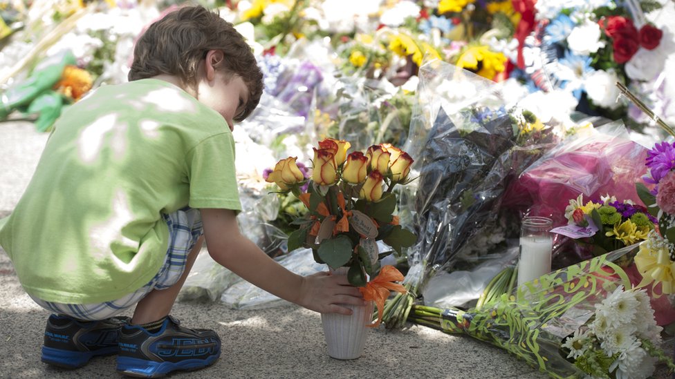 2015-06-19. Мальчик оставил цветы перед церковью Эмануэля АМЕ в Чарльстоне. В среду на собрании библейской группы были убиты девять человек. Колм О'Моллой для BBC News.