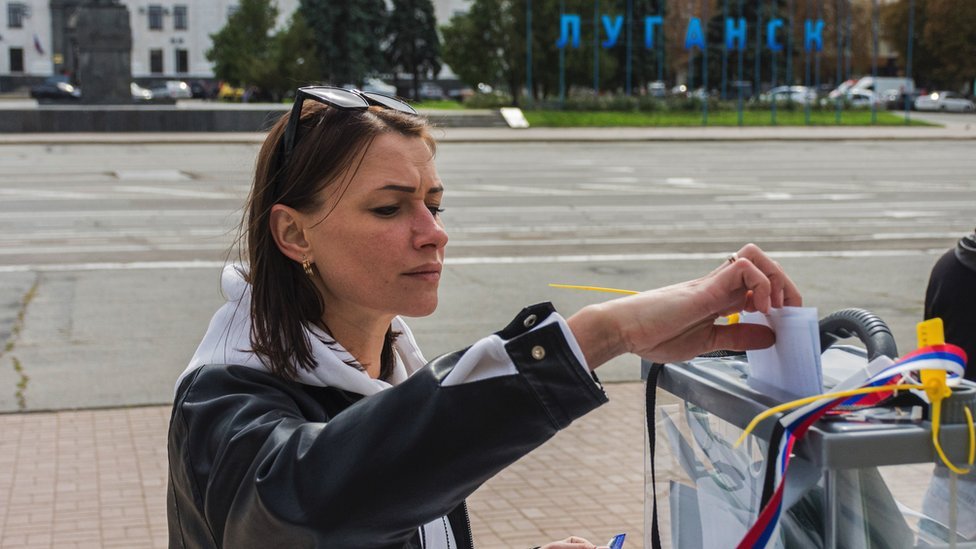 一名女性在盧甘斯克街頭的一個戶外投票站投票