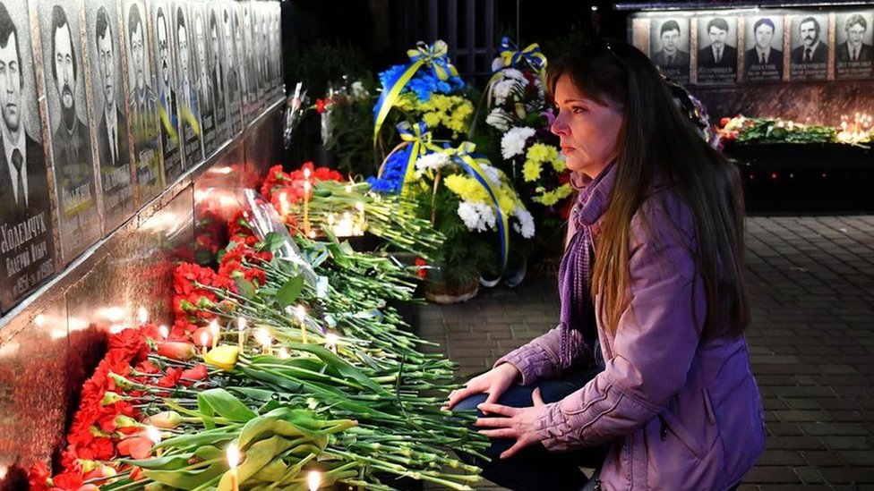 Una mujer deja flores frente a un homenaje a las víctimas de Chernóbil.