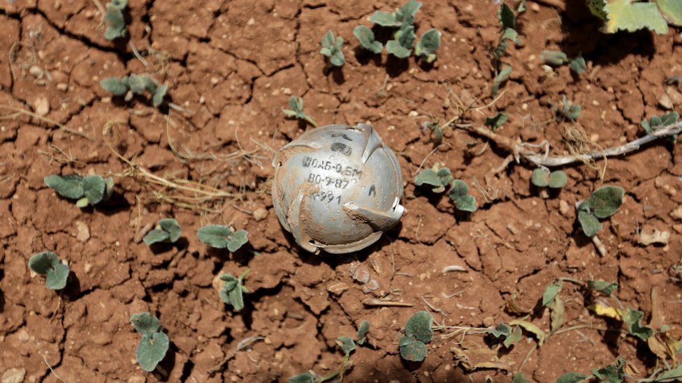 Кассетная бомба изображена на земле в поле в городе Ат-Тманах в южной части Идлиба, Сирия (21 мая 2016 г.)