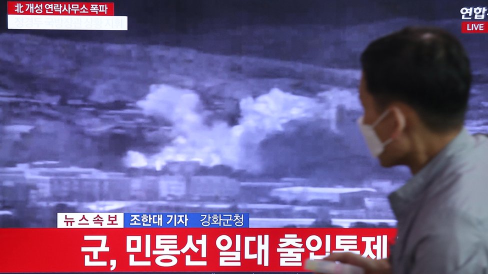 Человек смотрит последние новости об уничтожении межкорейского офиса связи в Кэсоне