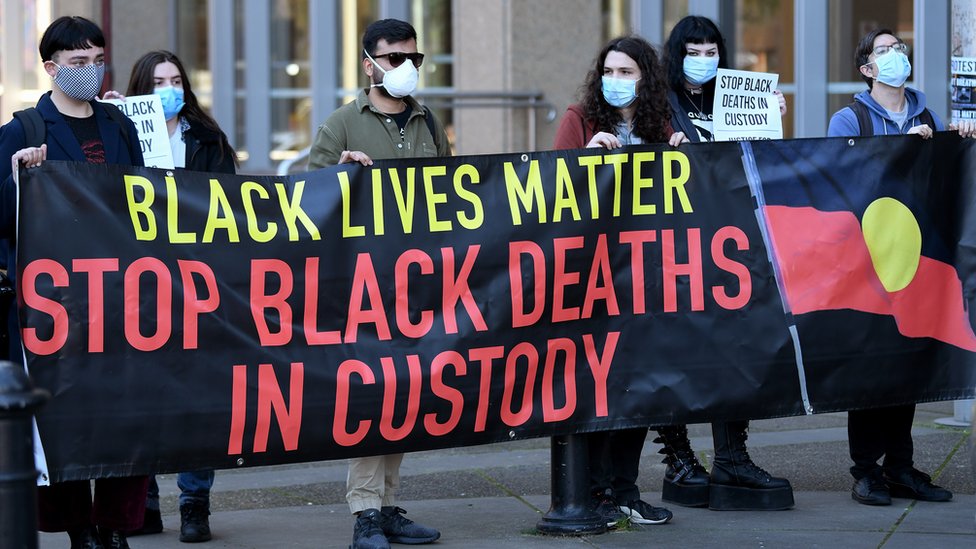 澳大利亞新南威爾士州最高法院外一群「黑人的命也是命」示威者舉起呼籲停止黑人在押期間死亡問題標語（23/7/2020）