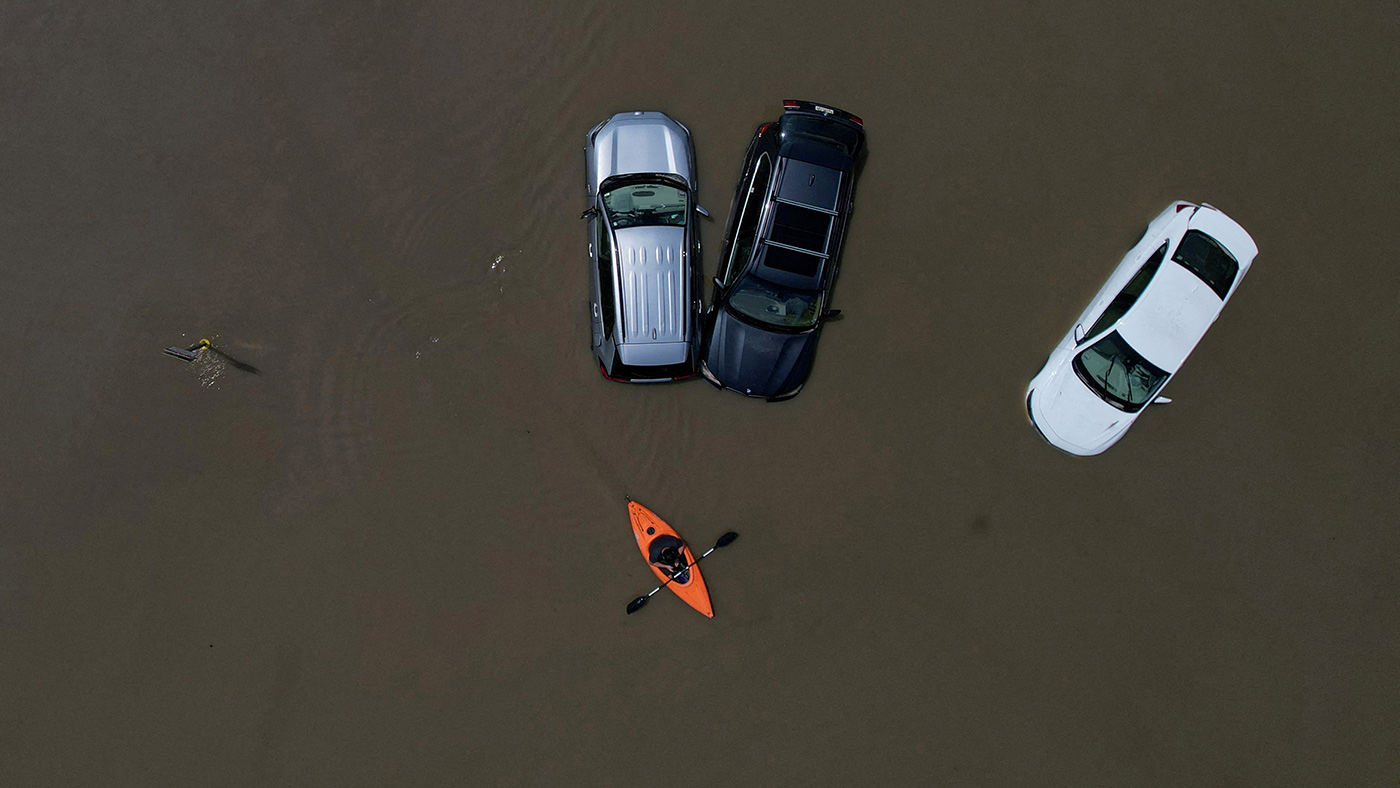 A person in a canoe passes cars partially submerged by flood waters from recent rain storms in Montpelier, Vermont - 11 July 2023