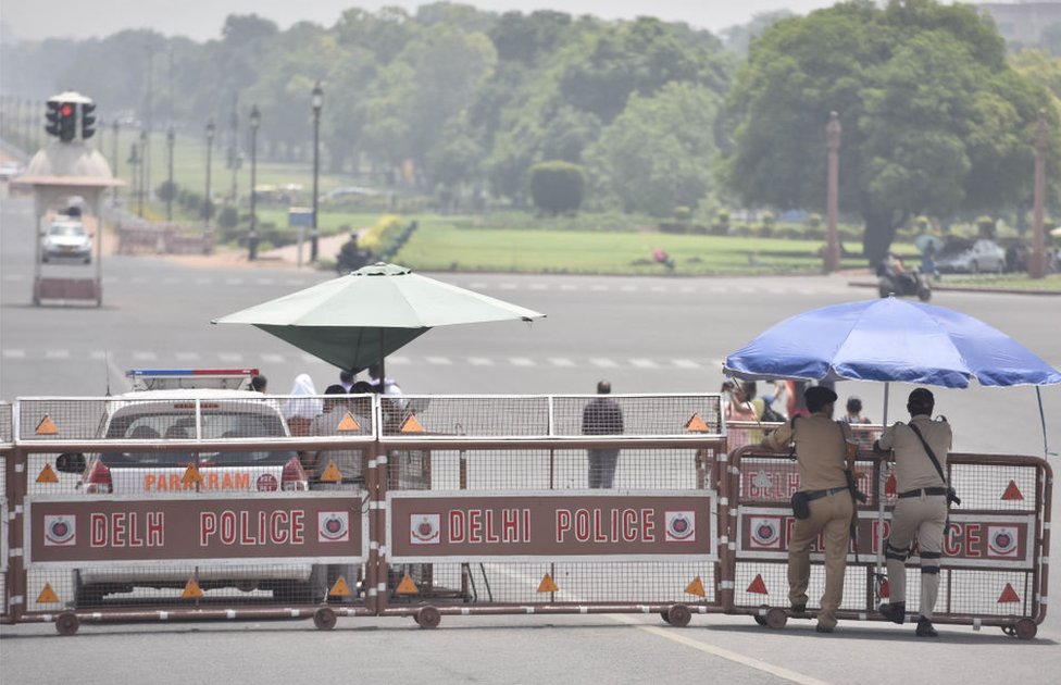 Полицейские под зонтиком стоят на страже жарким днем ??в Райсина-Хиллз, когда температура поднимается выше 45 градусов по Цельсию, 1 июня 2019 года в Нью-Дели, Индия.