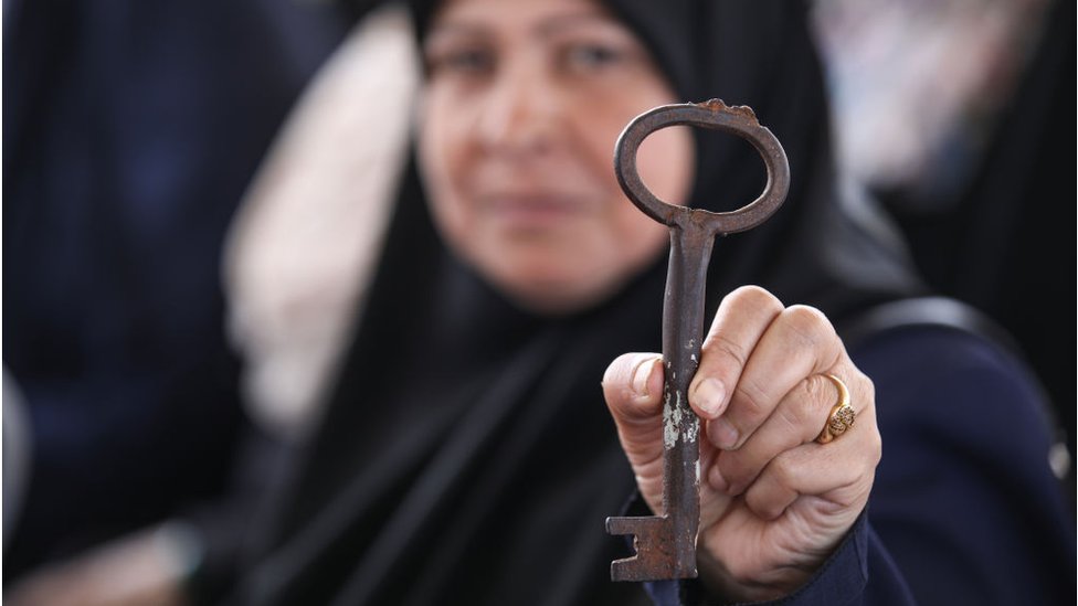 Una mujer palestina muestra una llave.