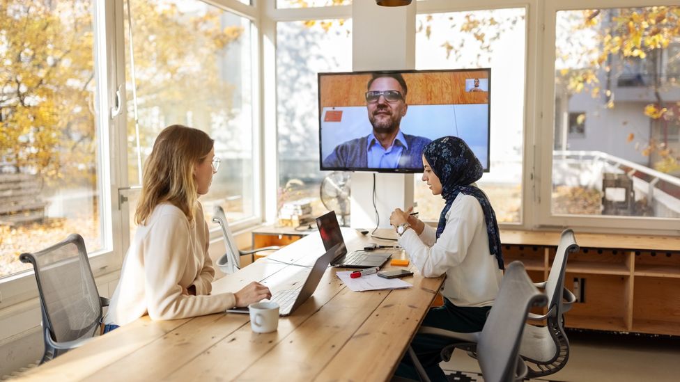 Reunião de trabalho híbrida em escritório com participação de funcionário por videoconferência