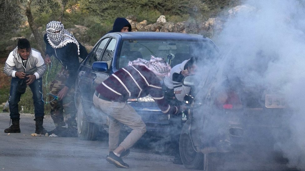 Палестинская молодежь укрывается под облаком слезоточивого газа во время столкновения с израильскими войсками возле Бейты на оккупированном Западном берегу (11 марта 2020 г.)