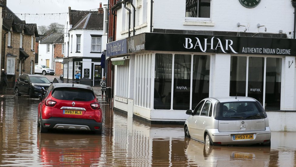 Автомобили стоят в отступающей воде от наводнения в Тенбери-Уэллс, Вустершир, после шторма Деннис.