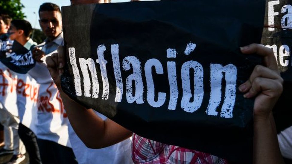 Manifestante protesta na Venezuela com cartaz com os dizeres 'inflação'