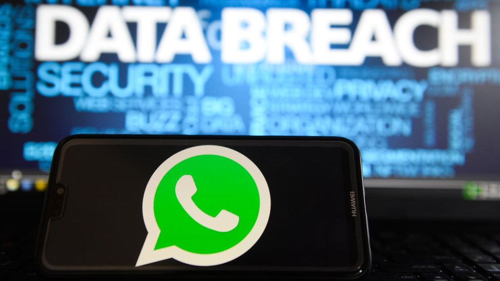 На этой фотографии логотипы Whatsapp видны на смартфоне Huawei со словом Data Breach на мониторе ноутбука