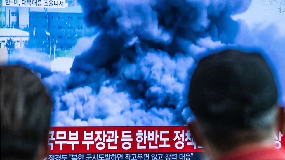 Пассажиры на вокзале Сеула смотрят новостной репортаж о том, как Северная Корея взорвала офис связи, который она делила с Южной Кореей 16 июня.