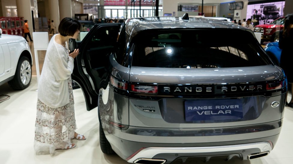 Женщина смотрит на Range Rover в автосалоне в Китае