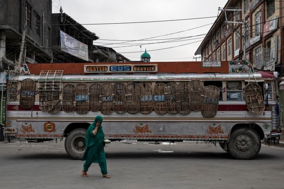 Кашмирская женщина проходит мимо автобуса, который служил в качестве блокпоста индийскими службами безопасности во время ограничений после отмены правительством особого конституционного статуса Кашмира в Сринагаре