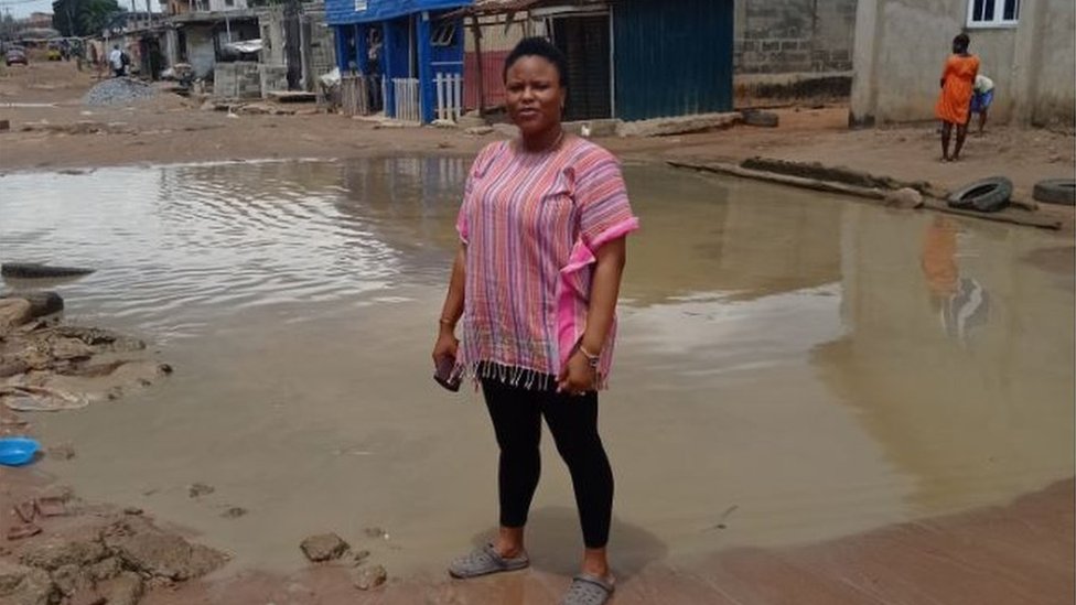 Opeyemi Kazeem-Jimoh stands near a pool of water in the street