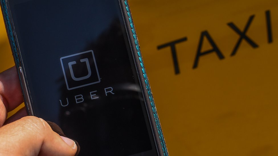 На этой фотографии 1 июля 2014 г. на мобильном телефоне рядом с такси отображается логотип нового приложения для смартфонов «Uber»