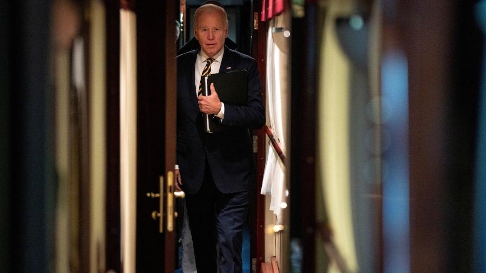 El presidente Joe Biden camina por un pasillo hasta su cabina en un tren después de una visita sorpresa al presidente ucraniano Volodymyr Zelenskiy.