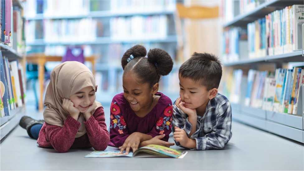 Crianças leem livros juntas na biblioteca
