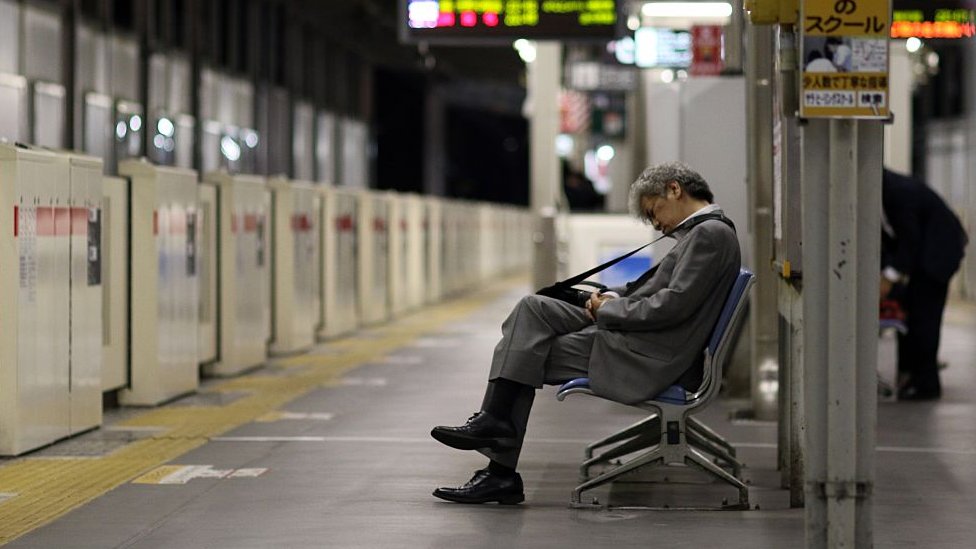 Empresario japonés dormido en una estación