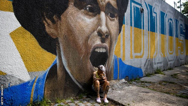 Boca Juniors women's player Yamila Rodriguez cries in front of graffiti image of Diego Maradona