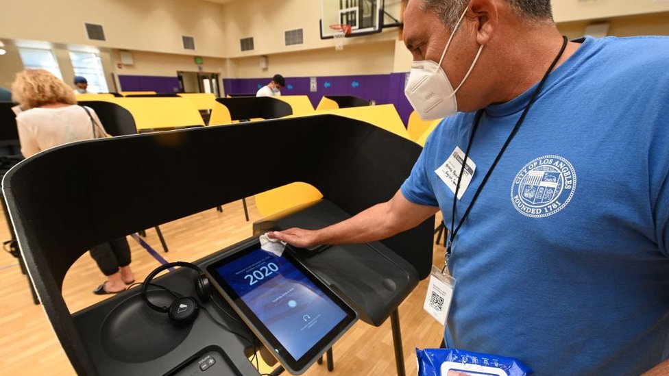 Poll worker cleans voting machine