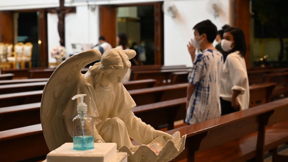 Sebuah botol pembersih tangan berada di pintu masuk gereja di Bangkok. Jemaat hadir beribadah dengan tetap menggunakan masker.