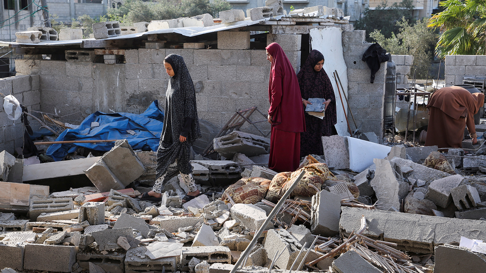 Women inspect as a house damaged in an Israeli strike lies in ruin, amid the ongoing conflict between Israel and Hamas, in Rafah