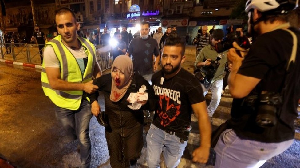 فلسطينيون ينقلون امرأة مصابة إلى مكان آمن