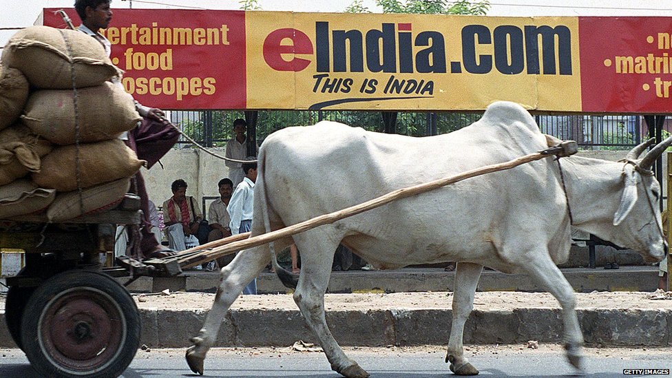 Тележка, запряженная волами, проезжает мимо рекламного щита автобусной остановки, рекламирующего один из многочисленных индийских интернет-порталов. 1 июня 2000 года в Нью-Дели.