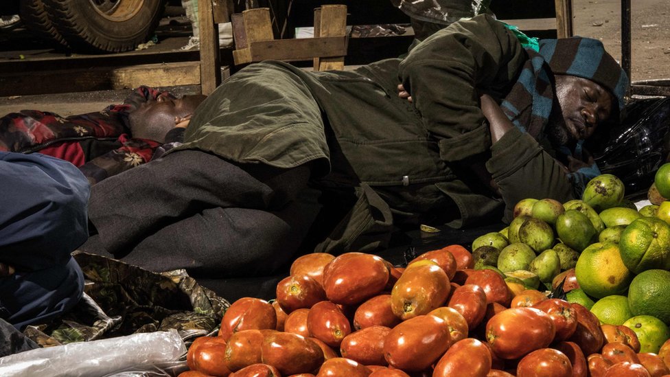 Торговец спит рядом с предметами для продажи на рынке в соответствии с директивой президента Уганды Йовери Мусевени о том, что все продавцы должны спать на рынках в течение 14 дней, чтобы ограничить распространение коронавируса COVID-19 на рынке Накасеро в Кампале, Уганда, в апреле. 7 февраля 2020 г.