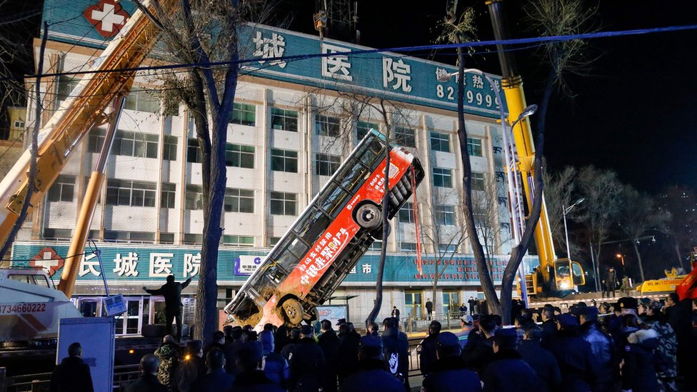 Rescuers lift a bus out of a sinkhole