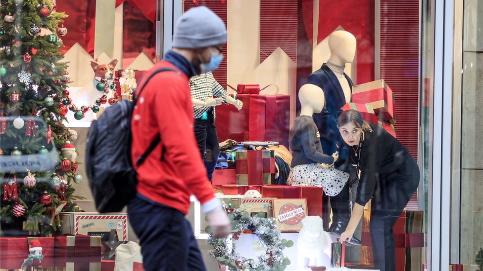 A man in a mask walks past a shop in Manchester