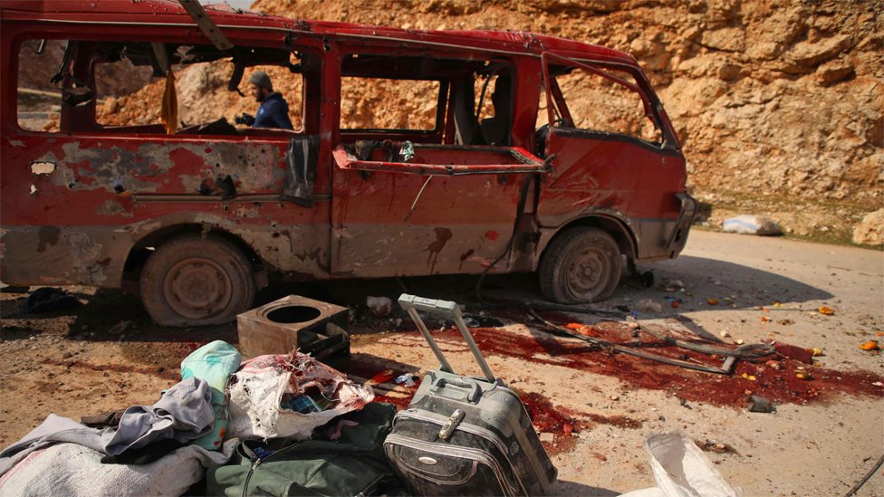 Люди осматривают микроавтобус, предположительно пострадавший в результате авиаудара России в провинции Алеппо (3 февраля 2020 г.)