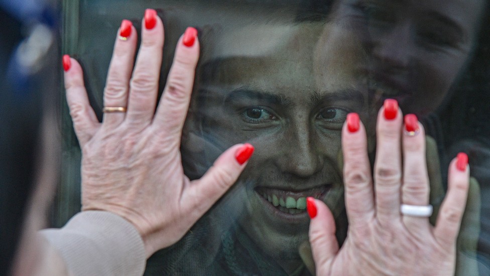 Manos de la madre de un conscripto ruso en las ventanas del autobús que transporta a su hijo