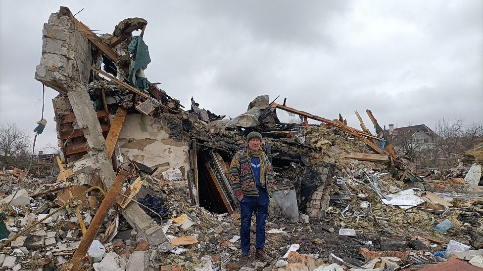 Un hombre frente a un edificio destrozado