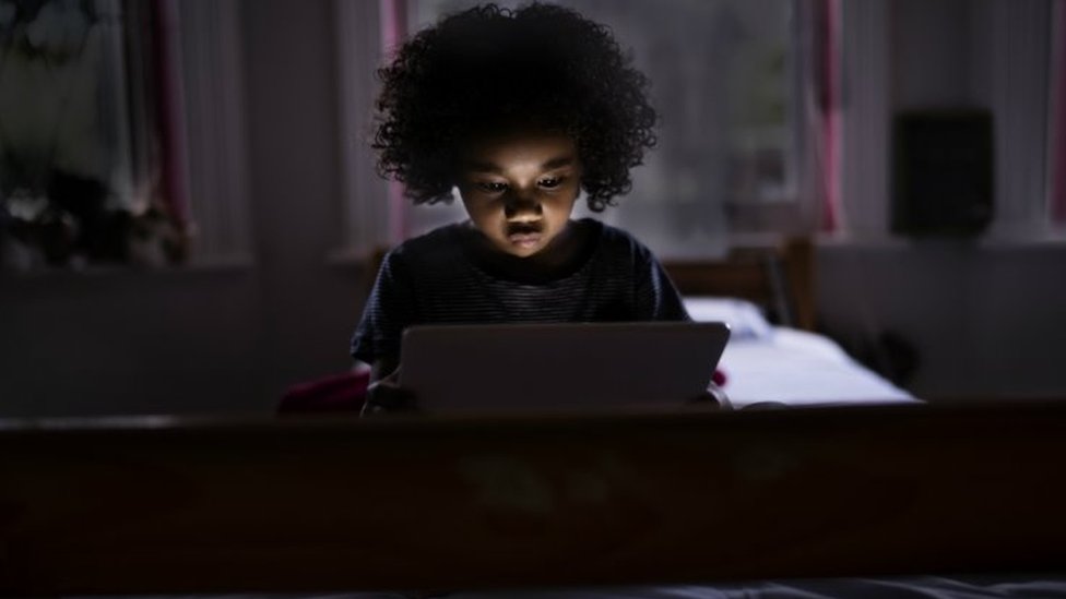 Criança vendo tablet à noite