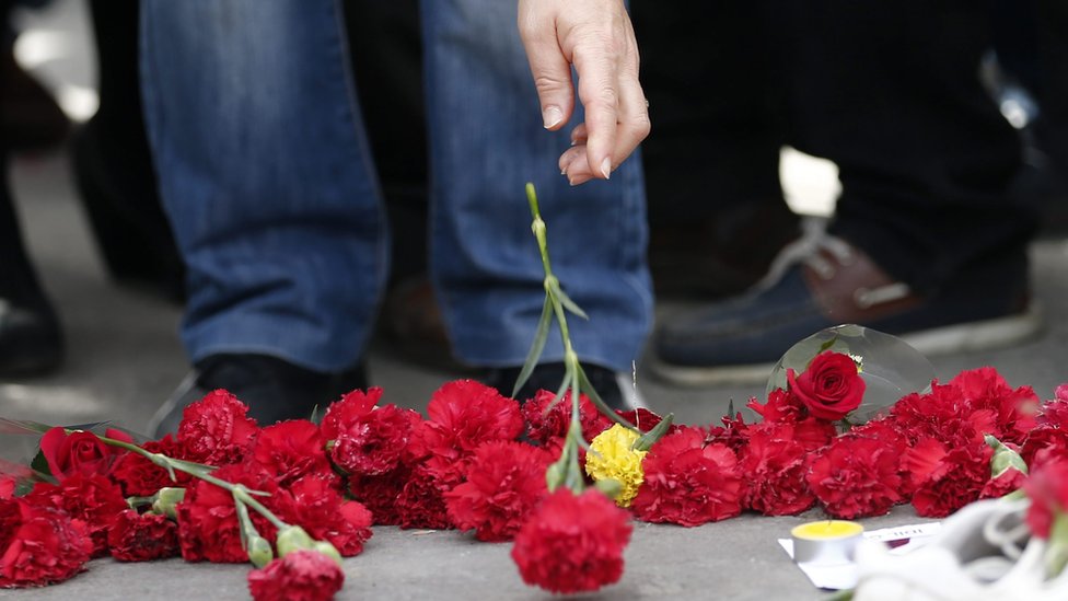 Люди кладут цветы на землю на второй день после взрывов после антиправительственной акции протеста в Анкаре, Турция