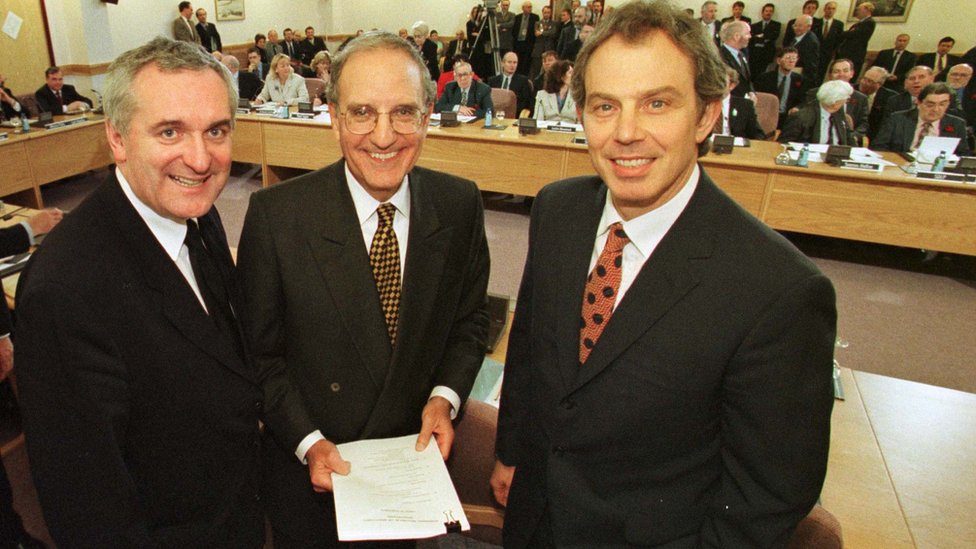 İrlanda Başbakanı Bertie Ahern, ABD Senatörü George Mitchell ve İngiltere Başbakanı Tony Blair 1998'de İrlanda adasındaki çatışmaları sonlandıran Hayırlı Cuma Anlaşması'na imza atarken