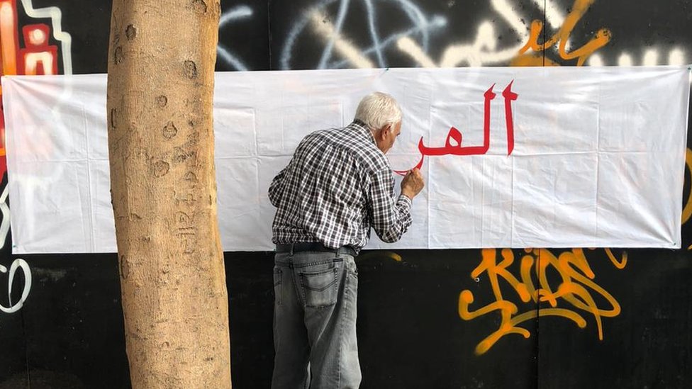 Old man writes anti-sectarian slogans on a wall in Beirut