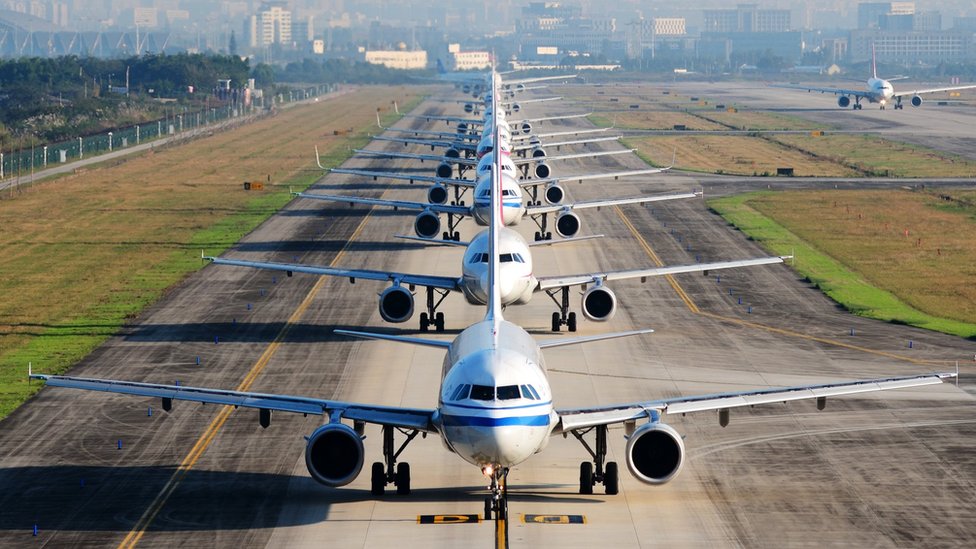 A number of aeroplanes lined up in an airport