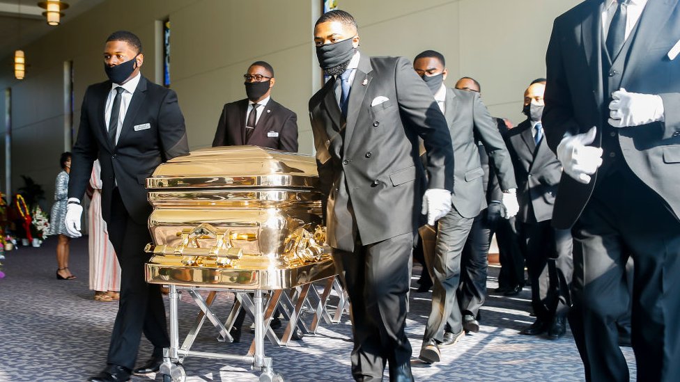 Pallbearers bring the coffin into the church