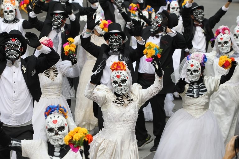 Люди в костюмах скелетов танцуют во время парада Катрины в Мехико 27 октября