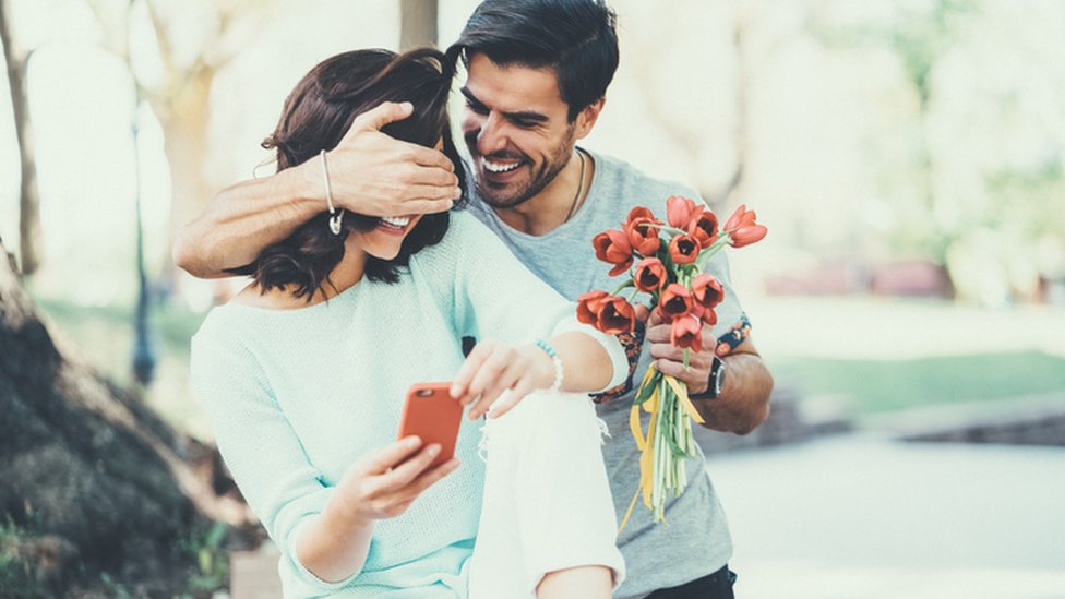 Un joven sorprendiendo a su novia con flores