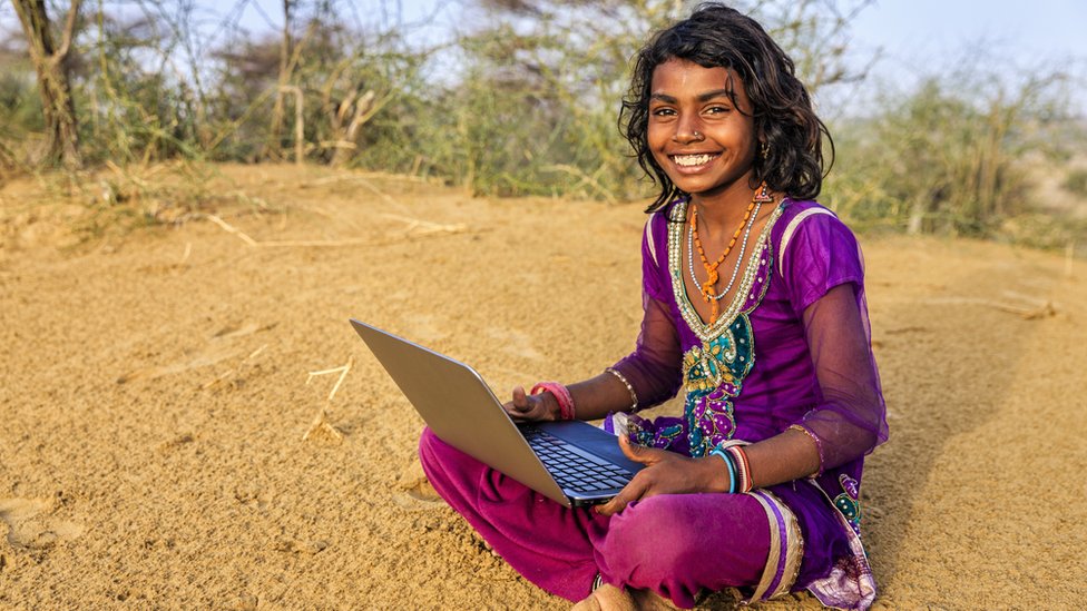 Niña en región rural de India con una computadora portátil