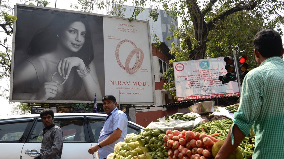 Индийцы проходят мимо рекламного щита с изображением болливудской актрисы Приянки Чопры, продвигающей роскошный ювелирный магазин Nirav Modi в Мумбаи 15 февраля 2018 г.