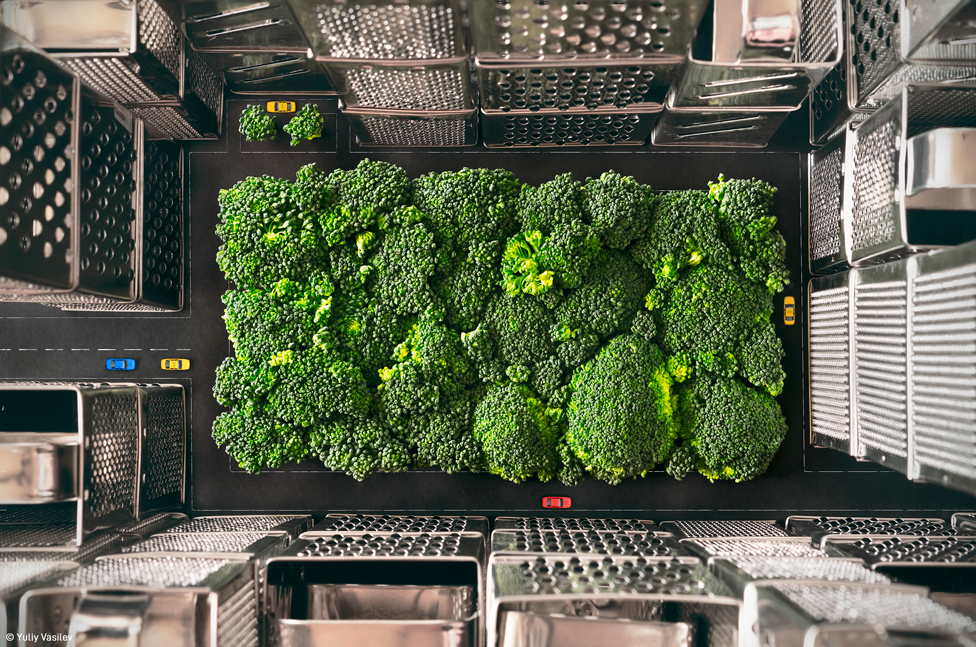Una fotografía aérea de brócoli rodeada de ralladores de metal y autos en miniatura, dando la apariencia de una ciudad vista desde el aire.